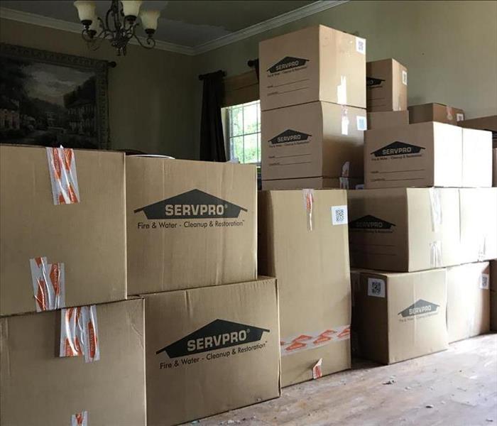 Stack of about twenty neatly stacked cardboard moving boxes adorned with the SERVPRO house logo.