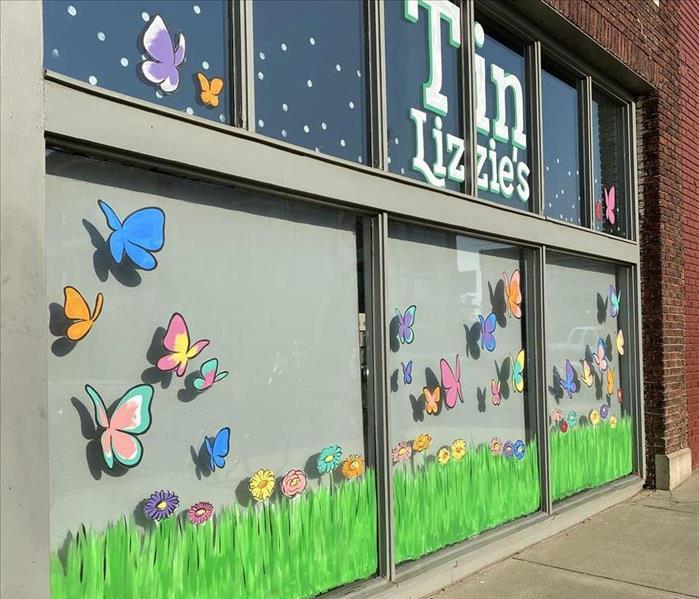 Storefront with green grass and multi-colored butterflies painted on the window.