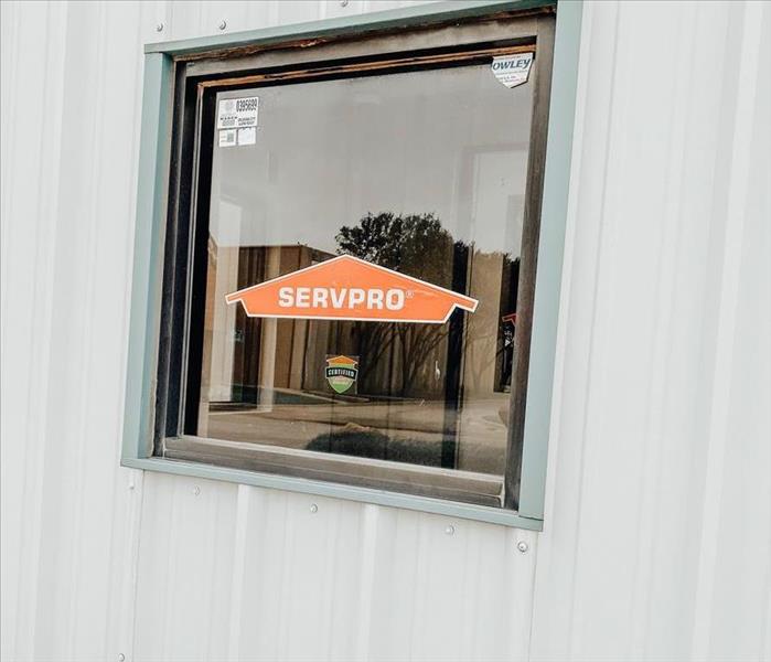 Orange SERVPRO house logo and Certified: SERVPRO Cleaned sticker on the window of a warehouse building.