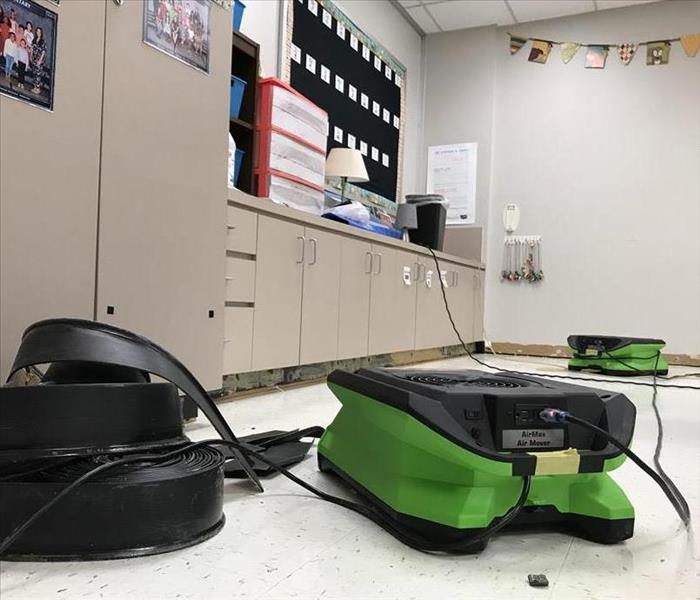Commercial air dryers set up on the floor of an elementary school classroom.