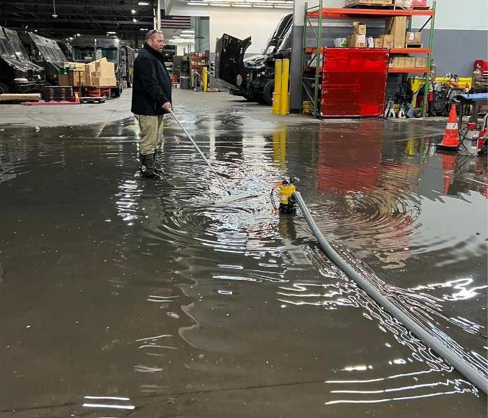 A man stands in water and extracts it inside a warehouse.