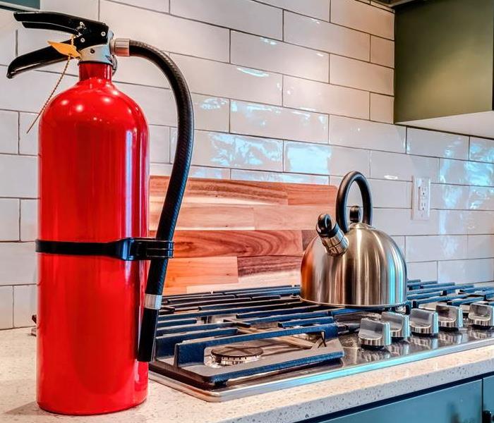 A red fire extinguisher sits on a kitchen counter