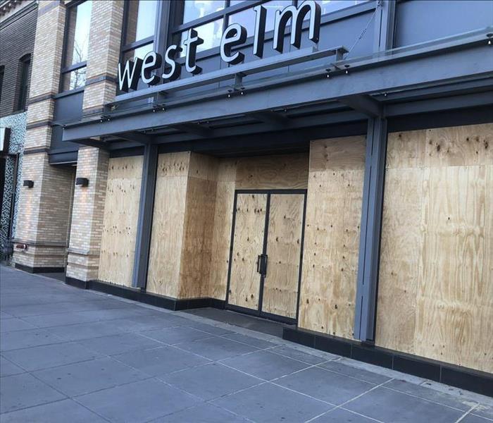 West Elm store with windows and glass doors boarded up.